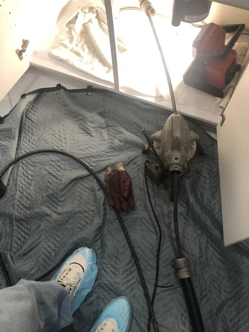 Drain cleaning machine and cable set up on a protective blanket in a customer's bathroom