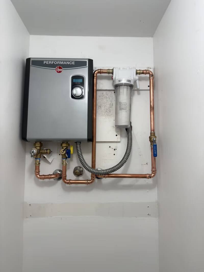 Newly installed electric tankless water heater with copper lines and an inline filter