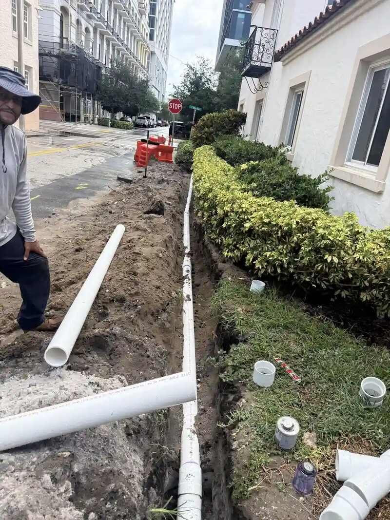 New white PVC line laid in an open trench beside a building in West Palm Beach