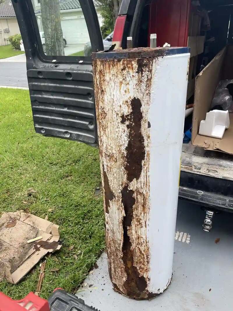 Rusted old tank water heater pulled out of a home and staged by the Drain Masters van