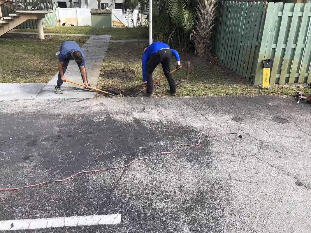 Two Drain Masters technicians digging beside a walkway to reach a buried sewer line