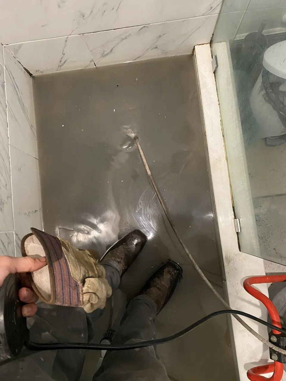 Drain cable fed into a shower drain from a drum machine to clear a clog