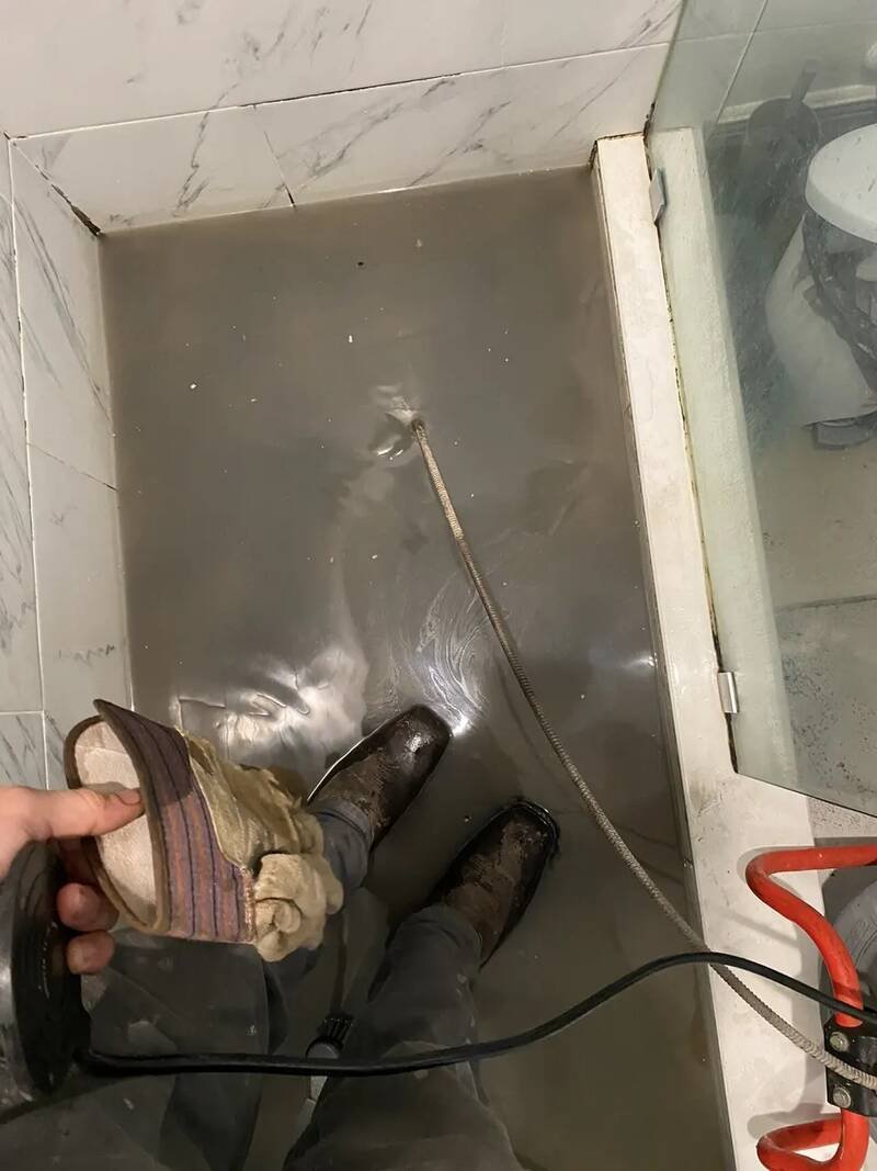 Drain cable fed into a shower drain from a drum machine to clear a clog