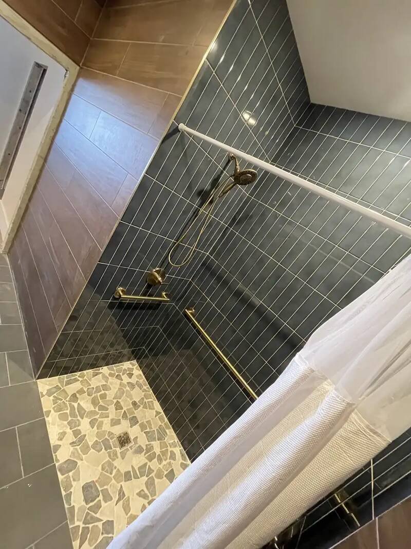 Tiled walk-in shower with a newly installed valve, shower head and handheld shower