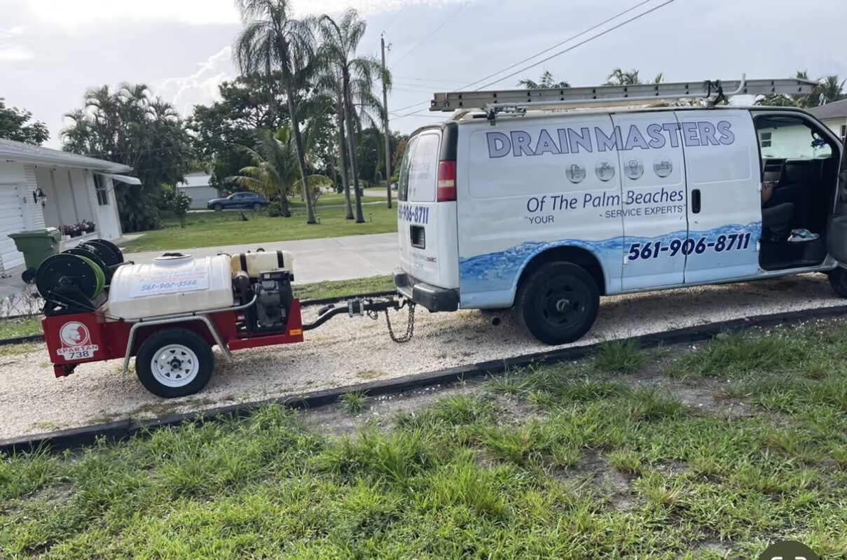 Drain Masters service van with a hydro jetting trailer parked outside a customer's home